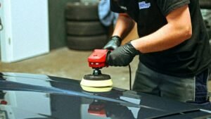 Detailer polishing a car exterior in a professional detailing studio